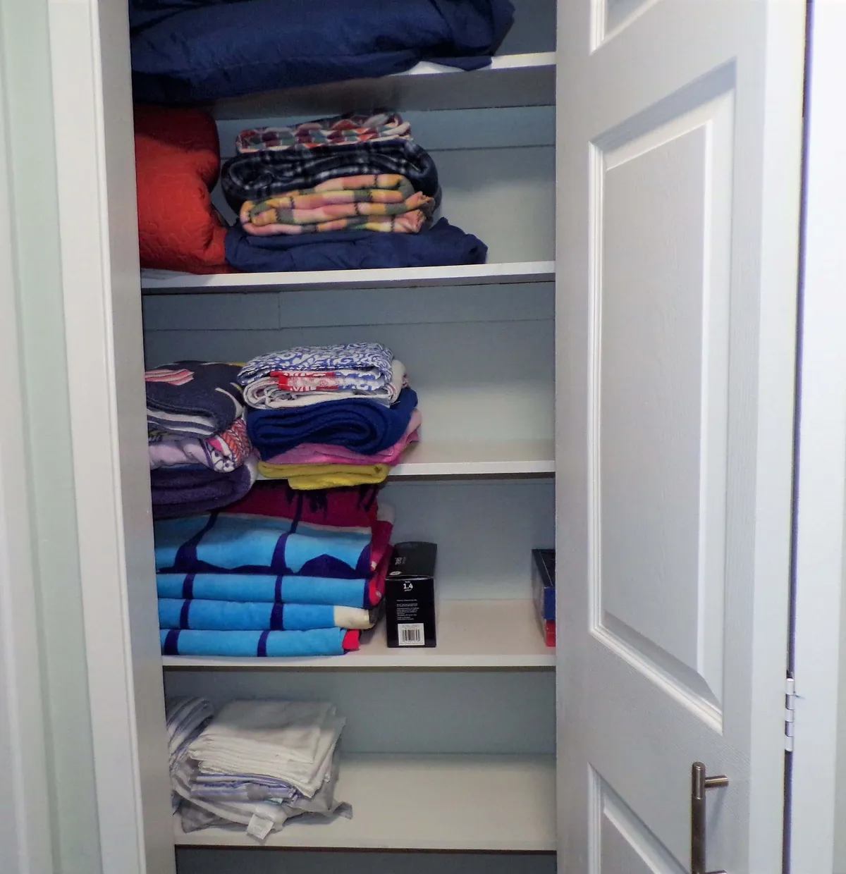 A neatly organized linen closet with shelves stacked with folded towels, linens, and beach towels, ready for use. The open closet door and visible supplies evoke readiness for pool and outdoor activities, ensuring guests have what they need for family fun.